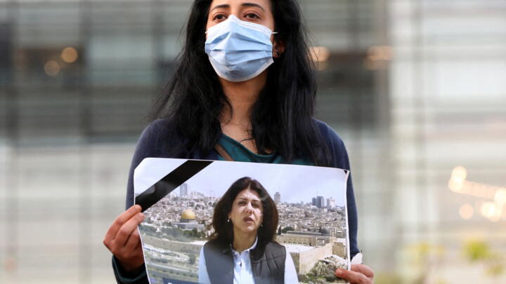A Lebanese journalist  in front of the UN building in Beirut holds a picture of Al Jazeera reporter Shireen Abu Akleh, who was killed during an Israeli raid in Jenin in the occupied West Bank, May 11, 2022.